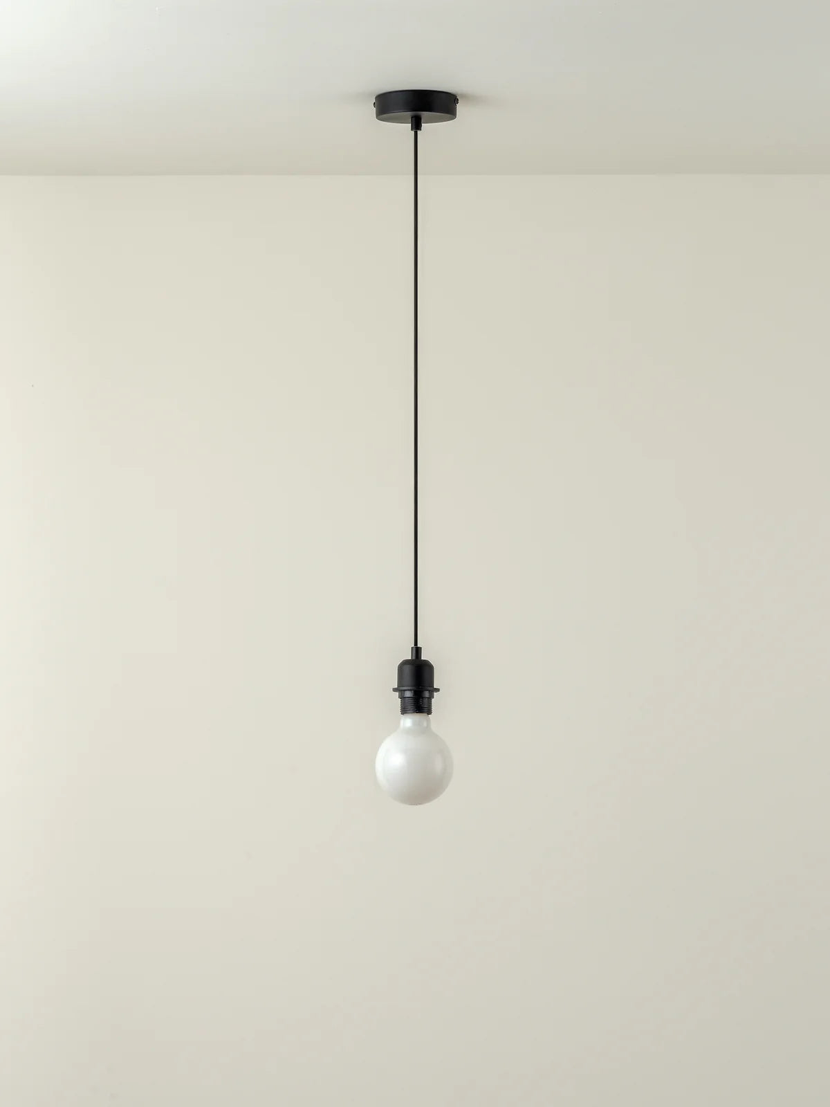 Single light bulb hanging from a black pendant - Loom Collection